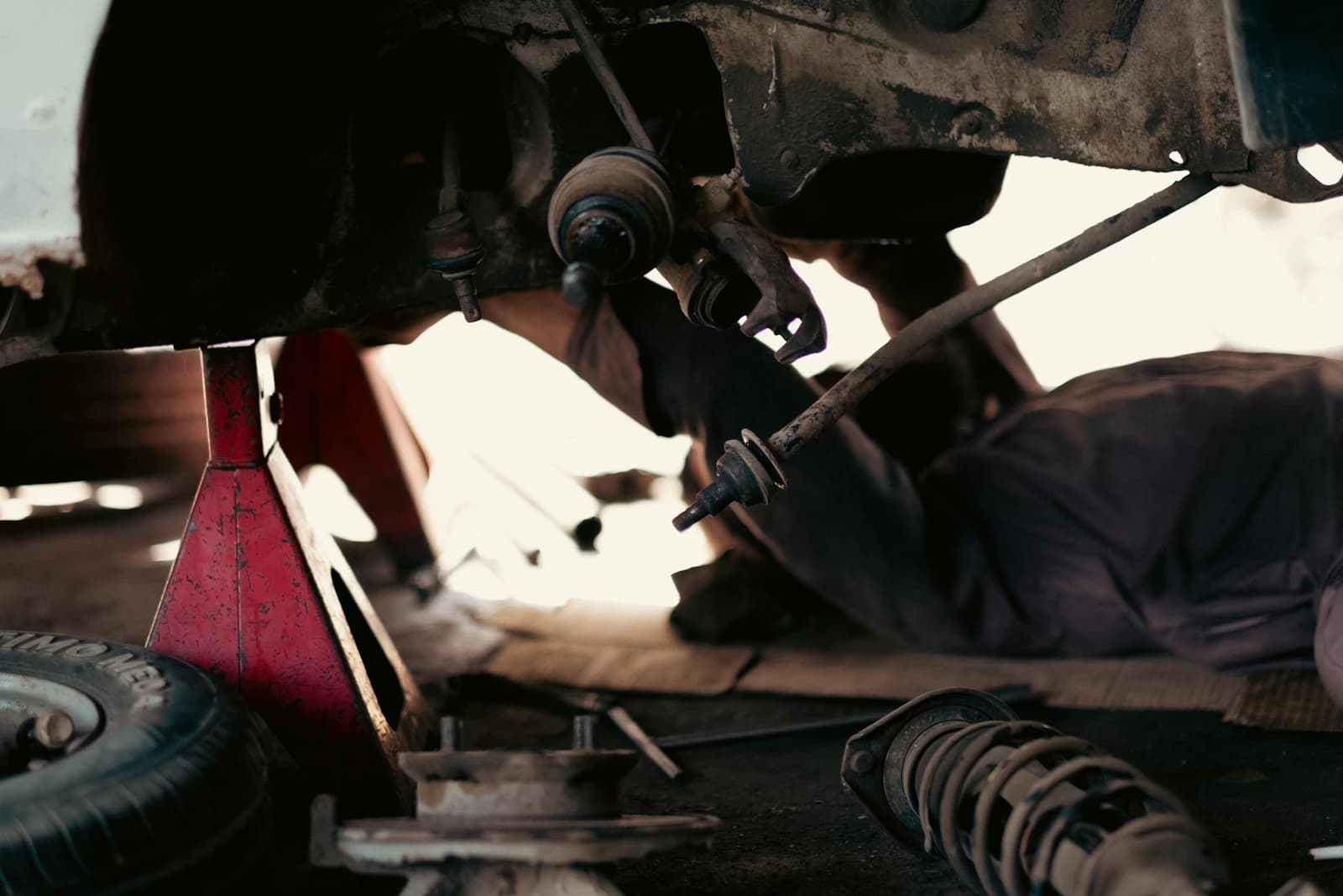 Auto sollevata su cavalletti, vista da sotto con sospensione e crick rosso